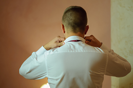 The man straightens the collar of his shirtの写真素材