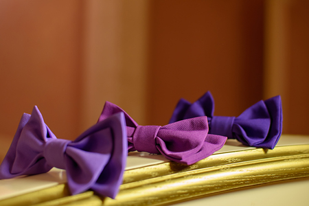 Three red bowtie on a yellow tableの写真素材