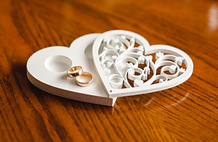 newlyweds wedding rings on a wooden heart-shaped standの写真素材