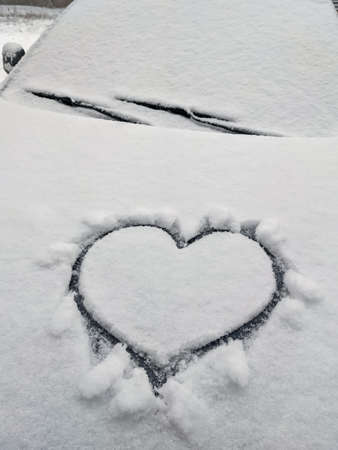 close up on drawing hearts on car windshield after snowの写真素材