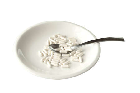 White isolated plate with pills and spoon の写真素材