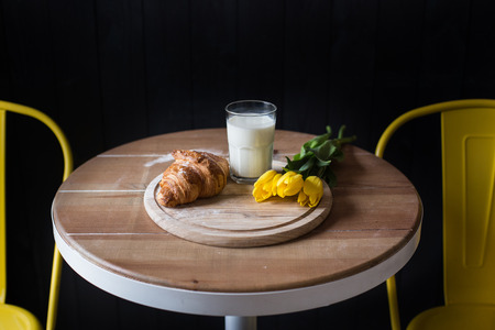 Croissants and tulips lie on a wooden table in a cafe waiting for the mother's dayの写真素材