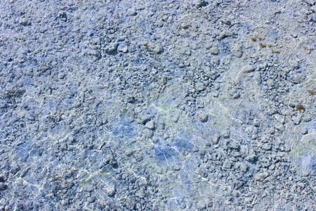 Pebble background at sun light. Stone texture in water.