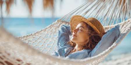 A tranquil woman with her eyes closed, wearing a straw hat, blissfully relaxes in a hammock on a sunny beach, with the shimmering turquoise ocean in the background, embodying the ultimate vacation serenity.の素材