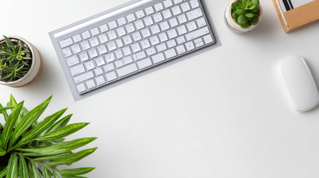Elegant workspace with modern aluminum keyboard, wireless mouse, and a trio of vibrant green potted plants on a clean white desk, promoting productivity and a refreshing work environment.の素材