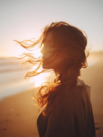 A close-up, intimate profile of a young woman on a beach at sunset, her long hair dramatically wind-blown and backlit by the warm, golden sun, evoking freedom, tranquility, and a natural, peaceful mood.の素材