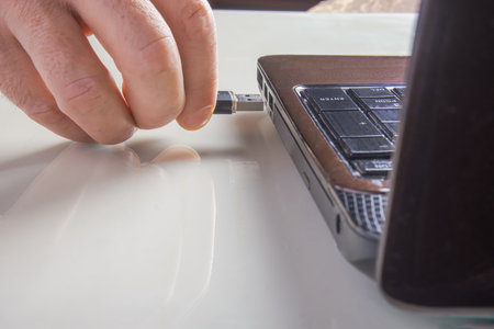 a man sticks a USB flash drive into a laptopの写真素材
