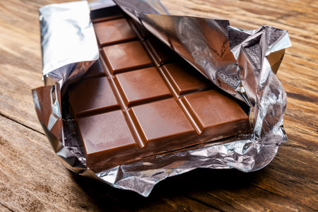 Chocolate bar in foil on a wooden backgroundの写真素材