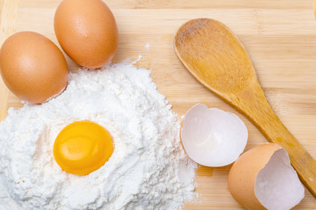 egg yolk, flour, two eggs and a wooden spoonの写真素材