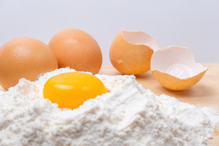 Flour, egg yolk, two eggs and a shellの写真素材