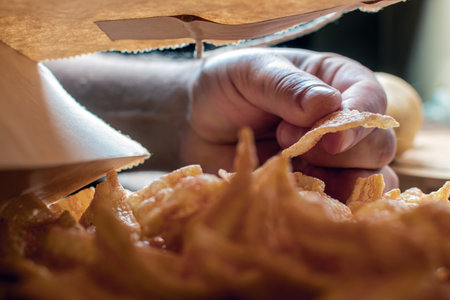 a man takes chips out of the packageの写真素材