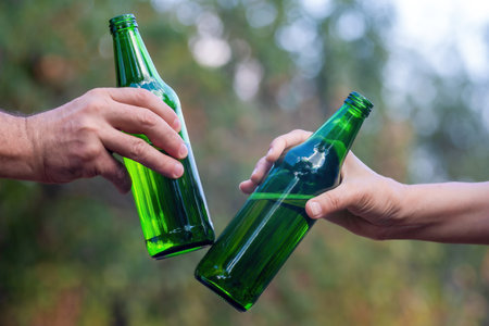 two hands male and female with beer bottles