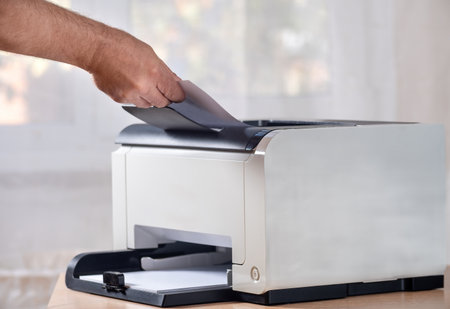 Close-up of a man's hands taking paper from a printerの写真素材