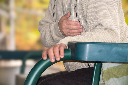 Senior man suffering from heart attack sitting on a chair in a hospital