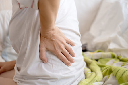 Close-up of a woman holding her hands on her painful back.