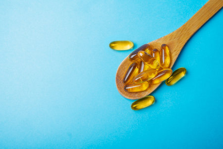 fish oil vitamin omega 3 in a wooden spoon on a blue backgroundの写真素材