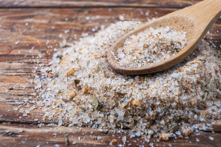 Close up of a wooden spoon full of salt on a wooden tableの写真素材