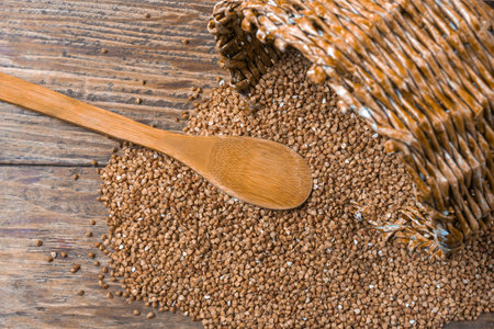 Buckwheat groats in a wicker basket and wooden spoonの写真素材