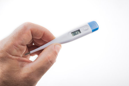 Hand holding a digital thermometer isolated on white background, closeupの写真素材