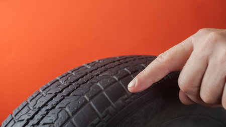 Close-up of male hand holding a car tire on red backgroundの写真素材
