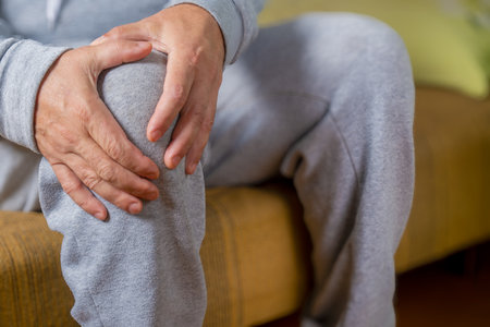 Mid section of senior man suffering from pain in the knee at homeの写真素材