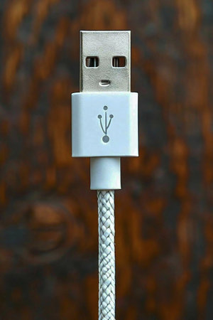 USB cable with plug on a wooden background, close-up.の写真素材