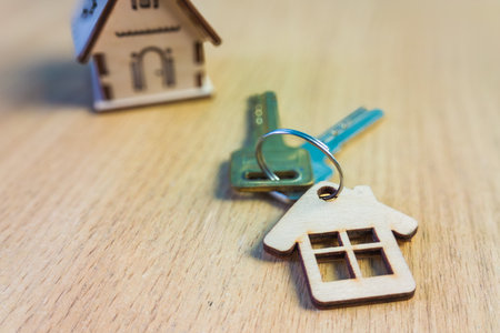 Miniature house with key on wooden background. Real estate concept.の写真素材