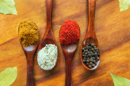 Spices and herbs in wooden spoons on a wooden background.の写真素材