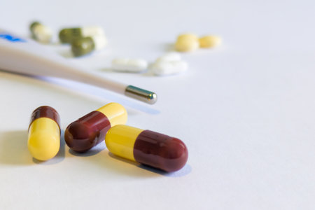 Pills and thermometer on white background. Focus on foreground.の写真素材