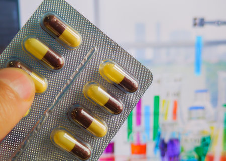 Capsules in a blister pack on a background of test tubes.の写真素材