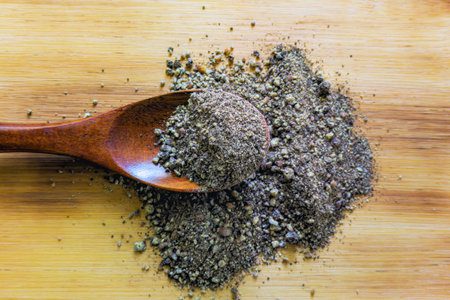 Heap of ground pepper in wooden spoon on cutting board background.の写真素材