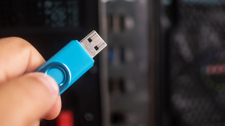 Usb flash drive in hand on the background of a computer.