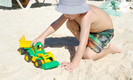 Little boy in a hat playing on the beach with toysの写真素材