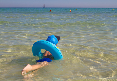 The little boy is swimming in the sea.
