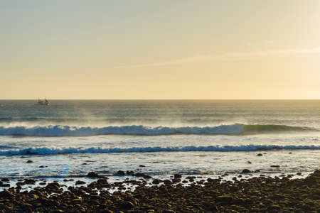 Beautiful waves and a small ship in the ocean. The Canary Islands. Spain. Seascape.の写真素材