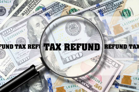 Tax Refund, View through a magnifying glass on the inscription on the background of Dollar bills. Business Finance. View from above.の写真素材