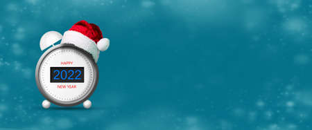 Alarm clock with numbers 2022. Santa hat. Blue background. New year banner. Copy space. Place for your text. Festive background. Background.の写真素材