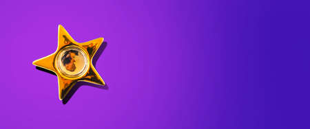 Gold star on a purple background. Hard shadow. Copy space. Place for your text.Flat lay. New Year's banner. Festive background.の写真素材