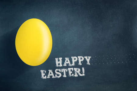 Yellow easter egg on a dark blue background. The inscription in chalk, Happy Easter.Easter background. Festive background.の写真素材