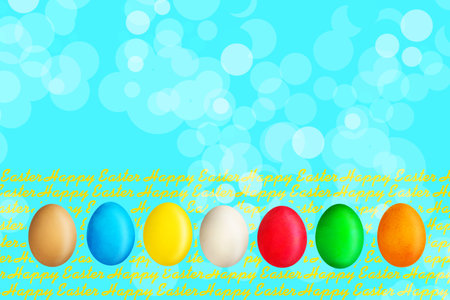 Happy Easter, word written on wooden blocks on blue background with multicolored easter eggs. Copy space. Place for text. Easter. Background.の写真素材
