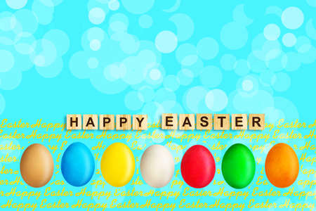 Happy Easter, word written on wooden blocks on blue background with multicolored easter eggs. Copy space. Place for text. Easter. Background.の写真素材
