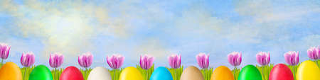 Beautiful tulips and colorful Easter eggs on a sunny cloudy sky. Easter background. Happy Easter banner. Background.の写真素材