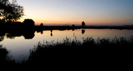 Sunset over the lake fishing on a warm summer eveningの写真素材