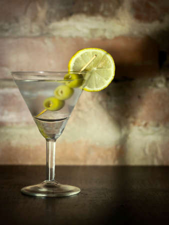 Martini with olives, lemon and ice on a background of an old brick wallの写真素材