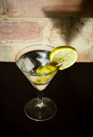 Martini with olives, lemon and ice on a background of an old brick wallの写真素材