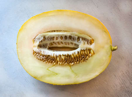 Ripe cut melon on a wooden table and a stone backgroundの写真素材