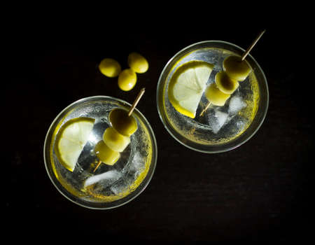 Martini with olives, lemon and ice on a black backgroundの写真素材