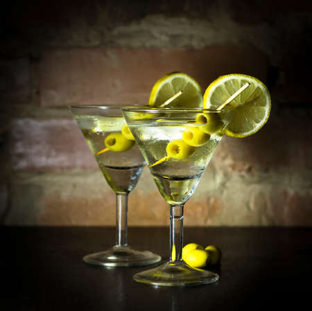 Martini with olives, lemon and ice on a background of an old brick wallの写真素材