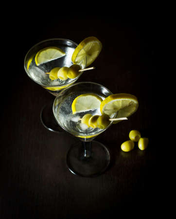 Martini with olives, lemon and ice on a black backgroundの写真素材