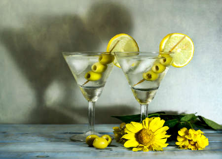 Martini with olives, lemon and ice on the old blue wooden tableの写真素材